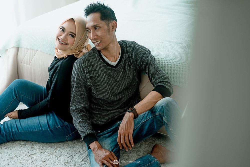 A couple relaxes casually together on a couch in comfortable clothing.