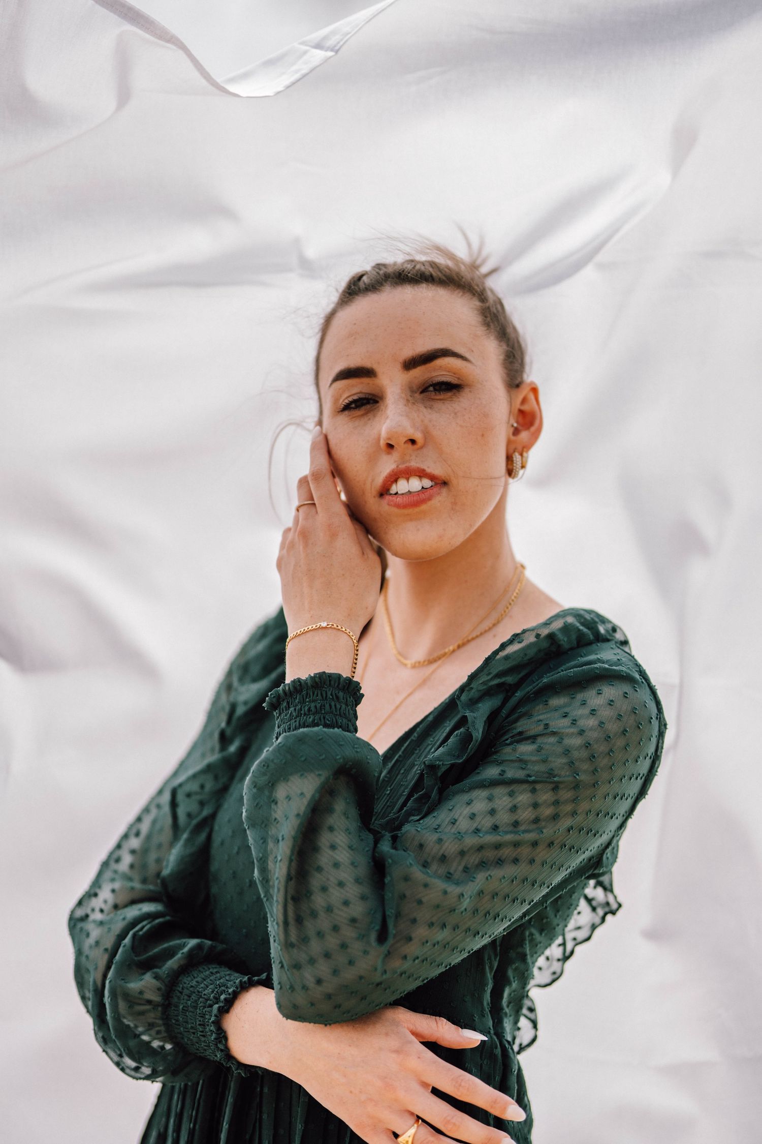 A portrait of someone in an emerald green dress against a white background.