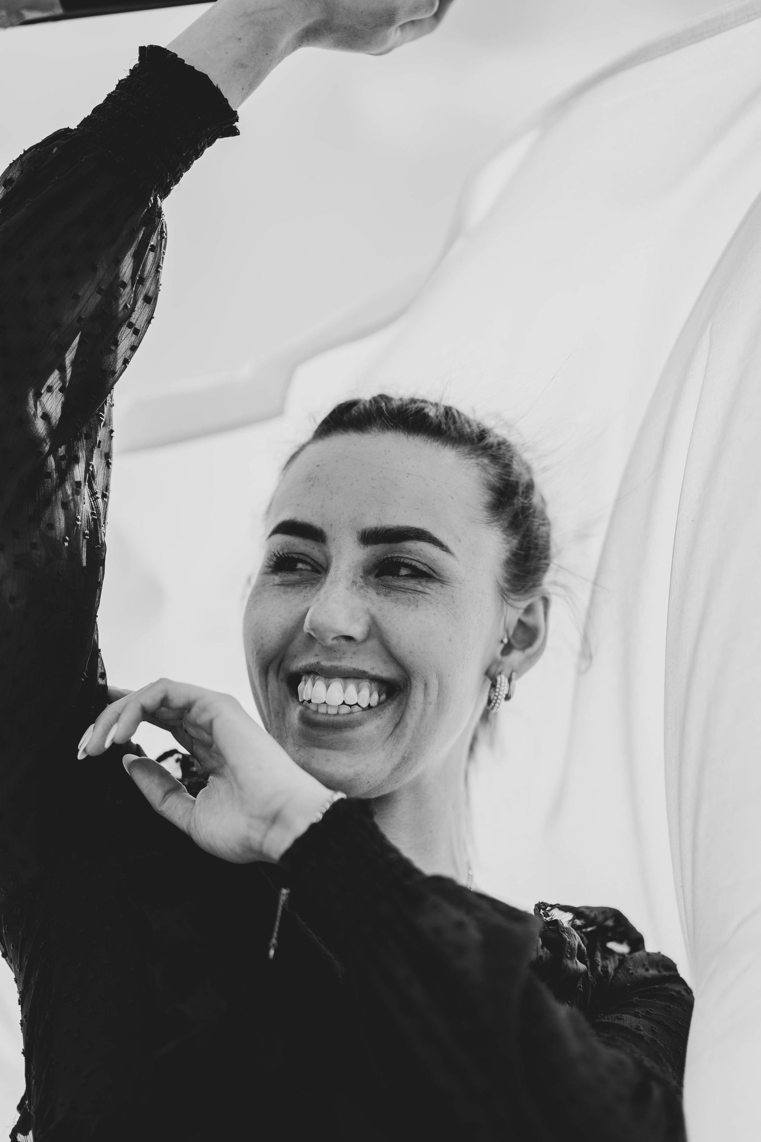 A black and white portrait capturing a joyful expression and raised arm.