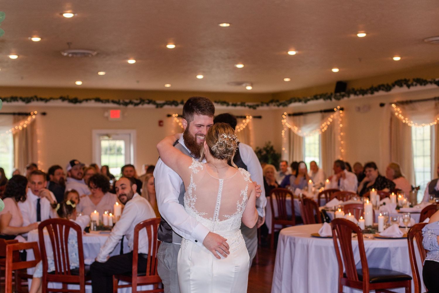 Couples dance together during a wedding reception in an elegant hall with decorative garlands.