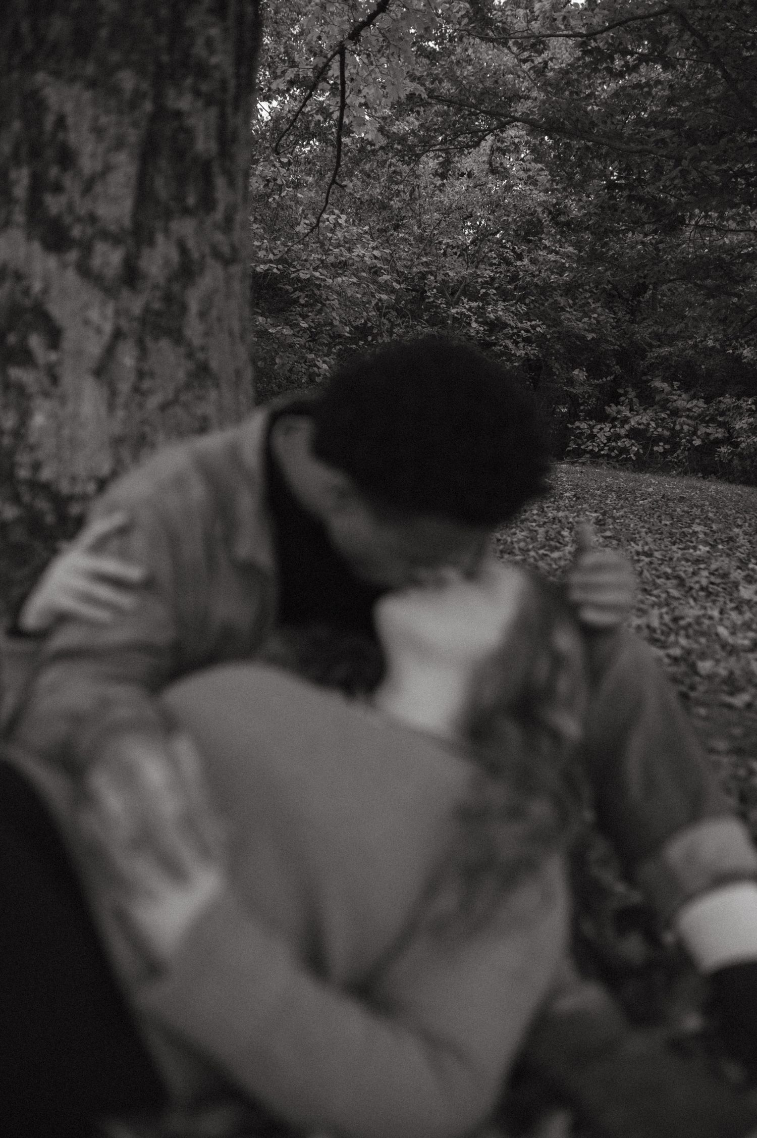 A black and white romantic moment captured in a wooded setting.