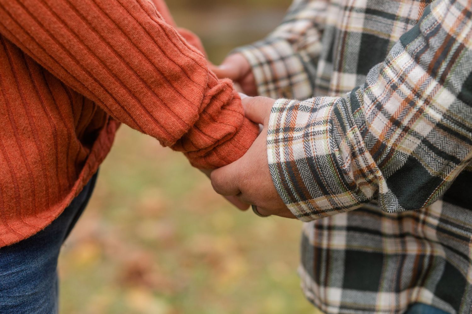 Couple sharing a romantic moment together in an autumn outdoor setting with plaid and orange attire.