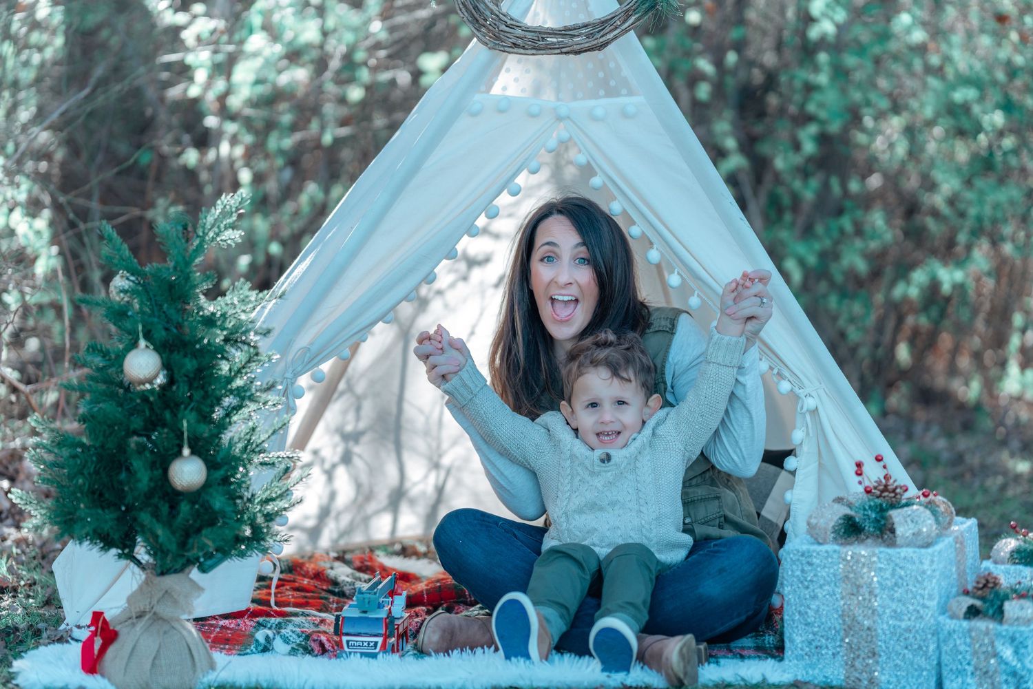 A playful moment captured in front of a white teepee tent with holiday decorations.