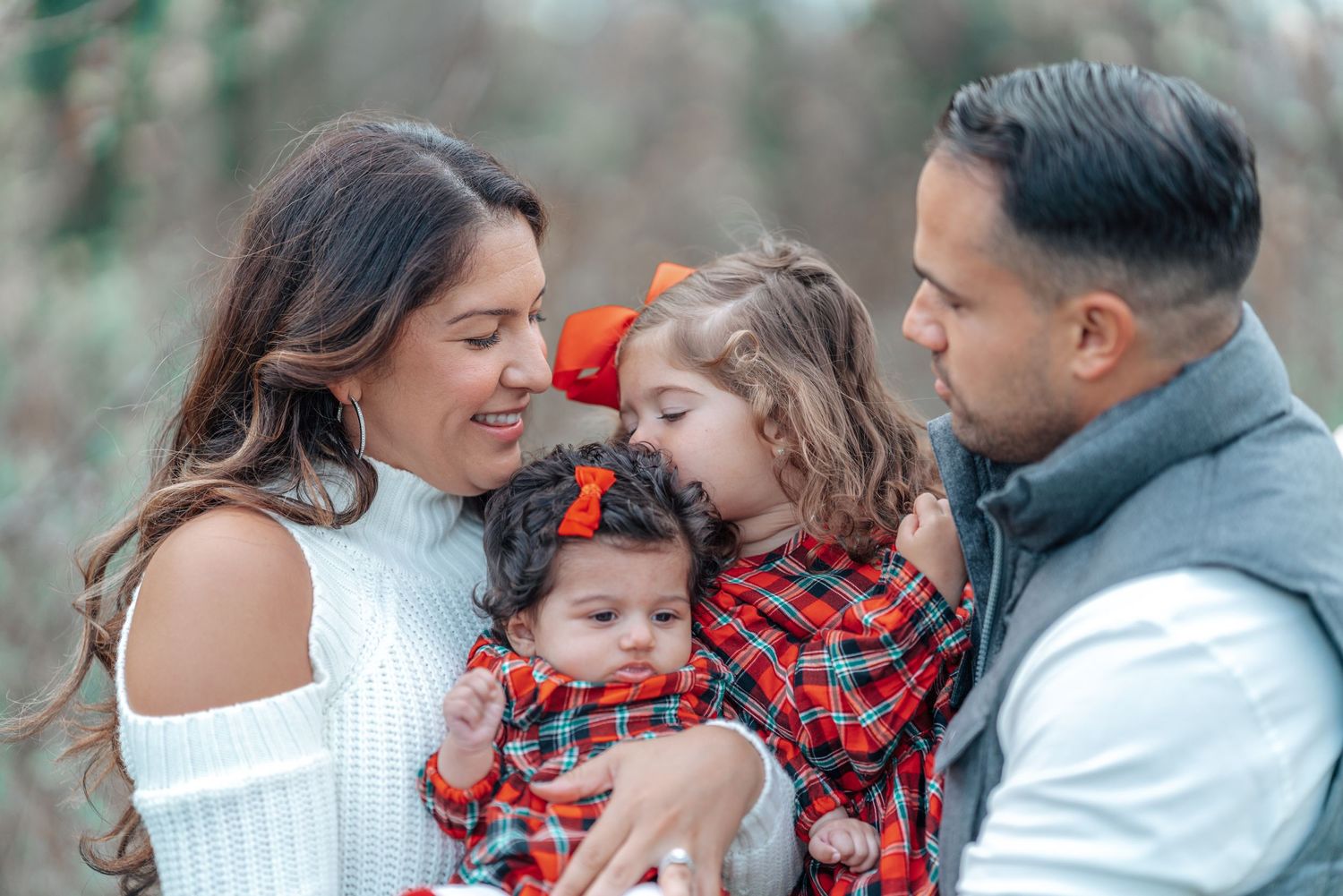Family sharing an intimate moment outdoors with matching winter outfits.