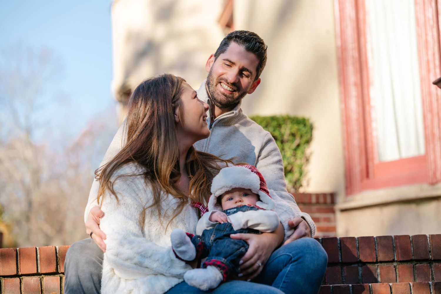 Happy family moment outdoors with a small baby sitting on brick steps.