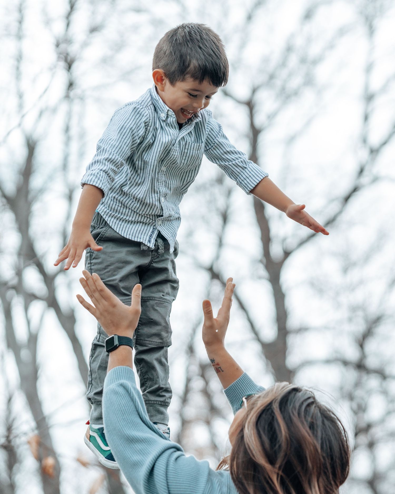 Child balancing in the air while being supported from below in outdoor setting.