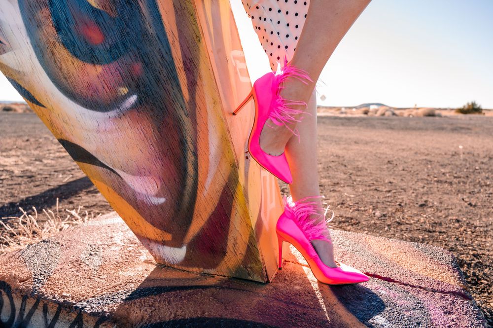 Hot pink stilettos stand out against a painted desert art installation.
