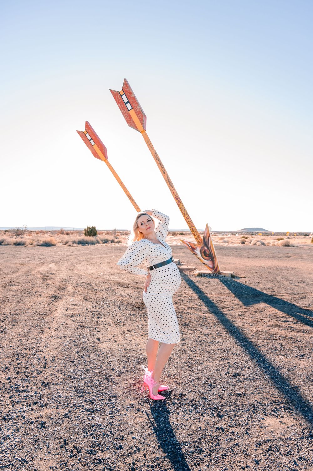 A retro-styled desert photoshoot featuring giant wooden arrows and a polka dot dress.