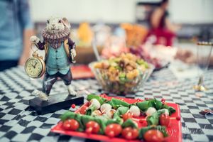 Vintage style tea party setup with character figurine and fresh vegetables on checkered tablecloth.