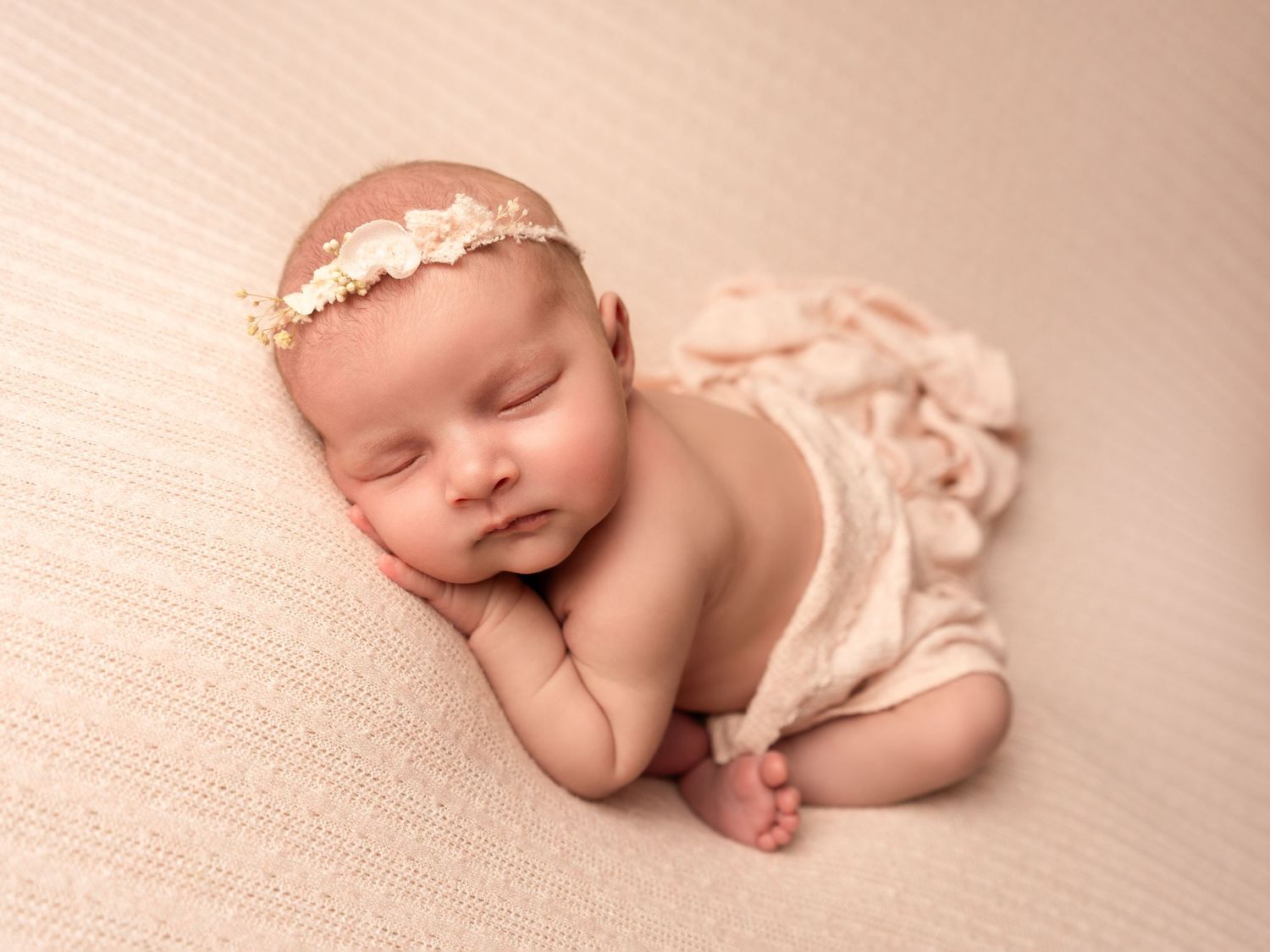 Baby girl sleeping on pink blanket with floral headband by professional newborn photographer in Doncaster.