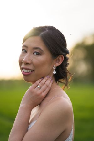 Beautiful Asian bride posing at sunset with elegant drop earrings and upswept hair.