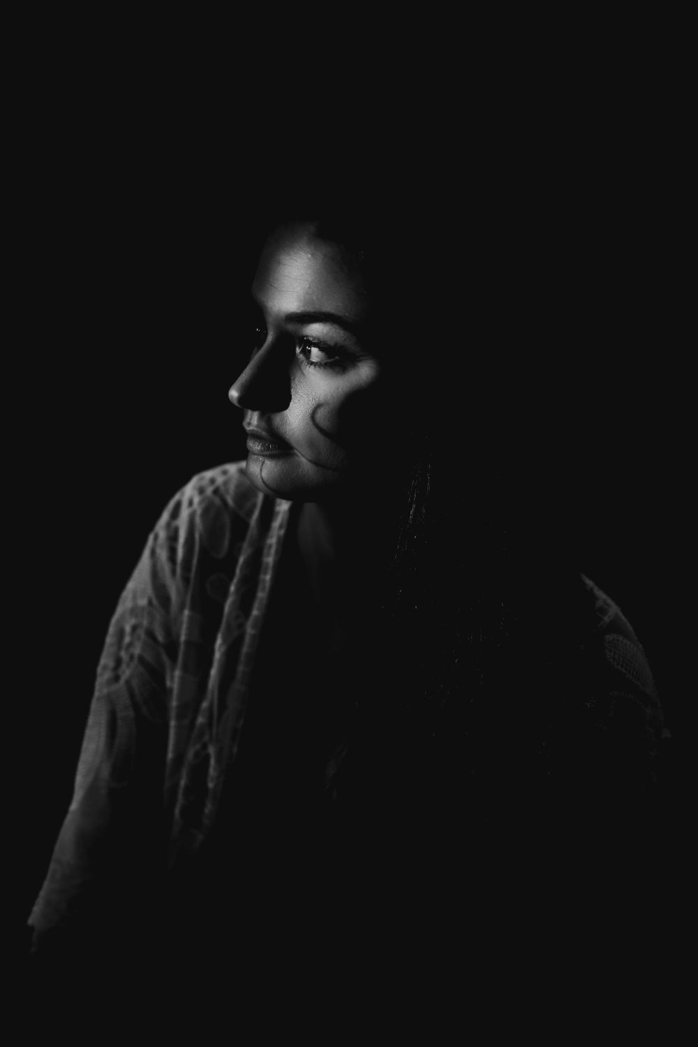 Dramatic low-key portrait with minimal lighting creating mysterious shadows.