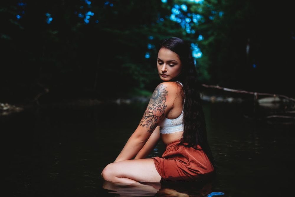 Portrait session by water featuring moody artistic lighting and natural scenery.