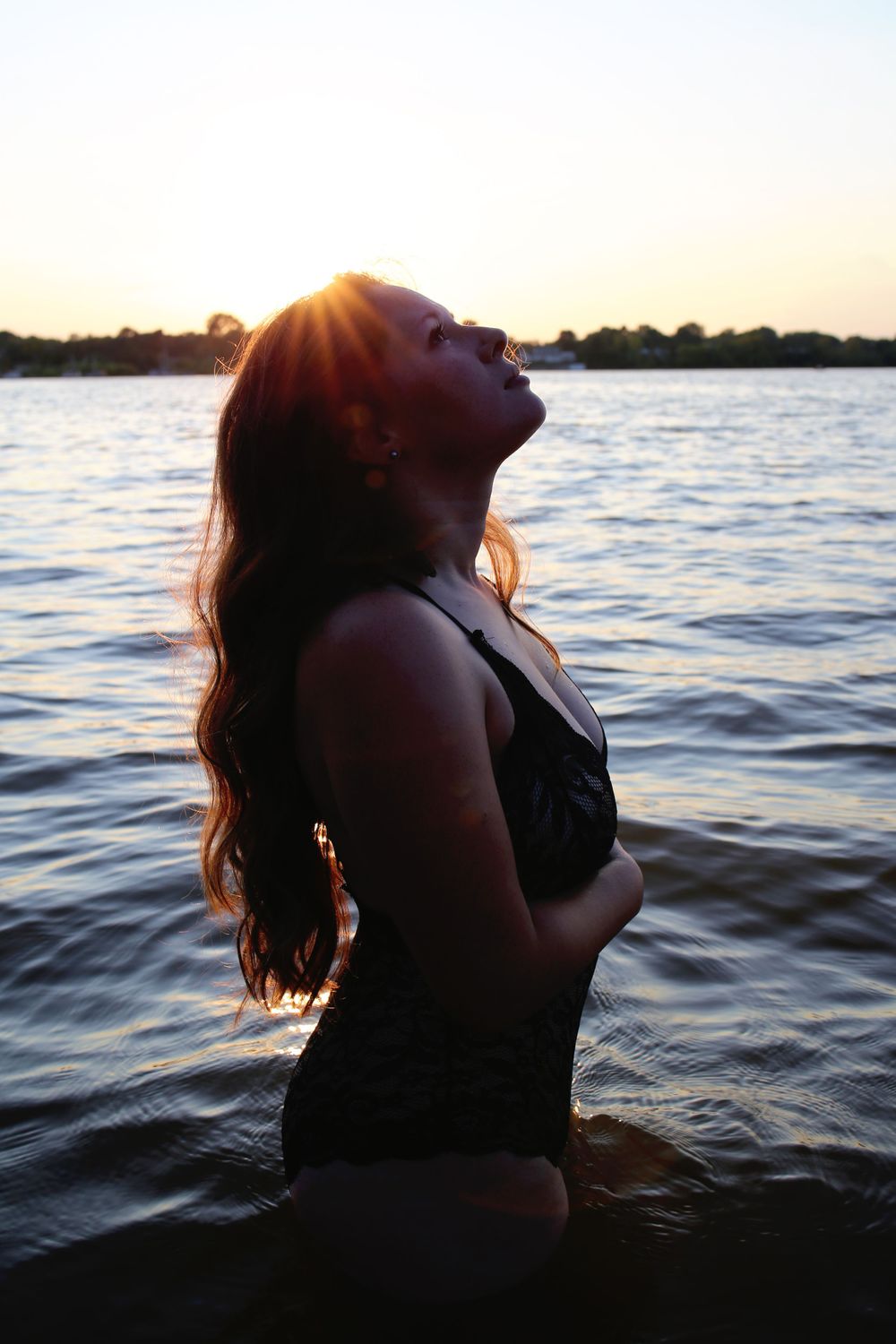 Artistic silhouette portrait at sunset over serene lake waters.