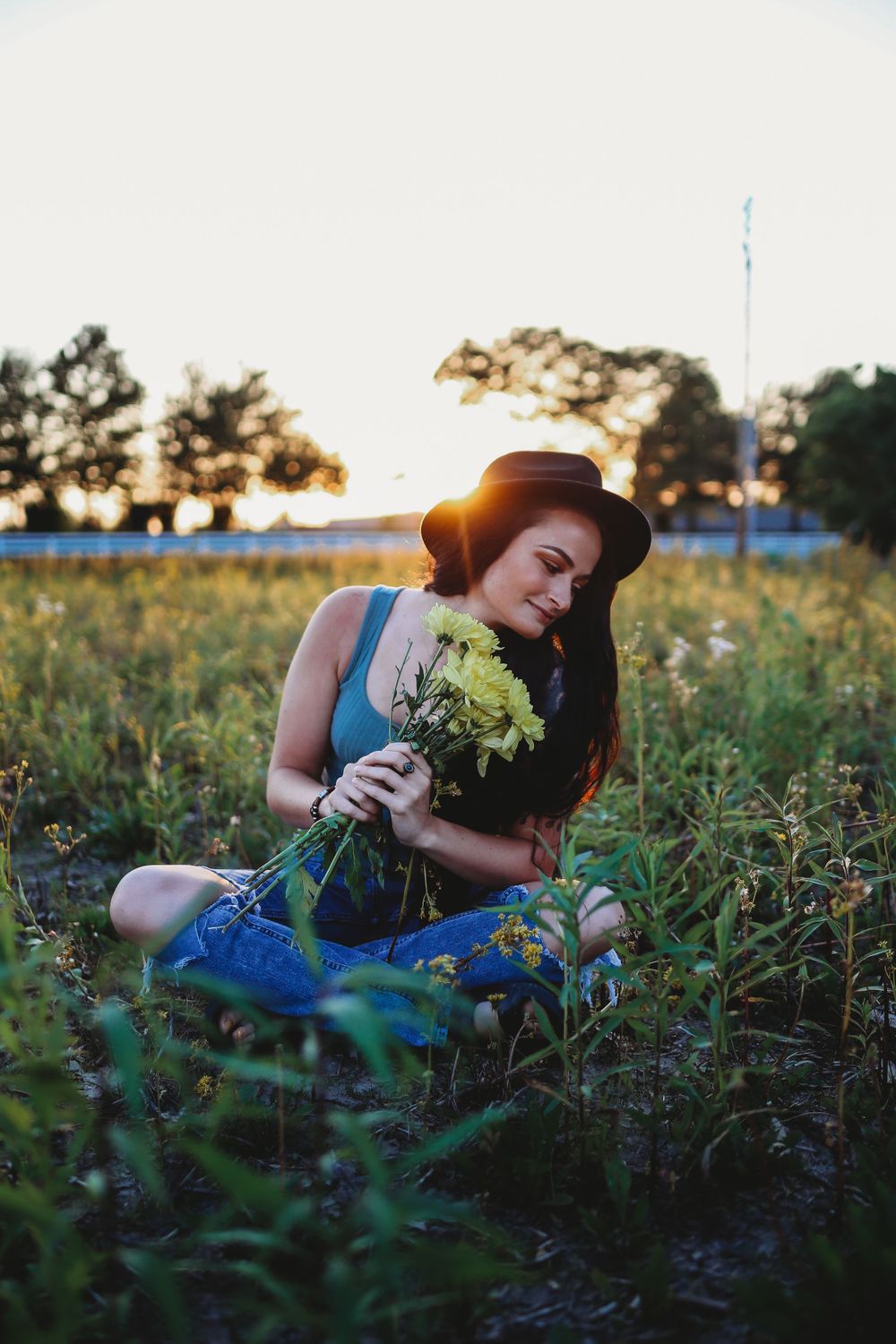 Artistic outdoor photo featuring yellow flowers and denim in a golden sunset field.