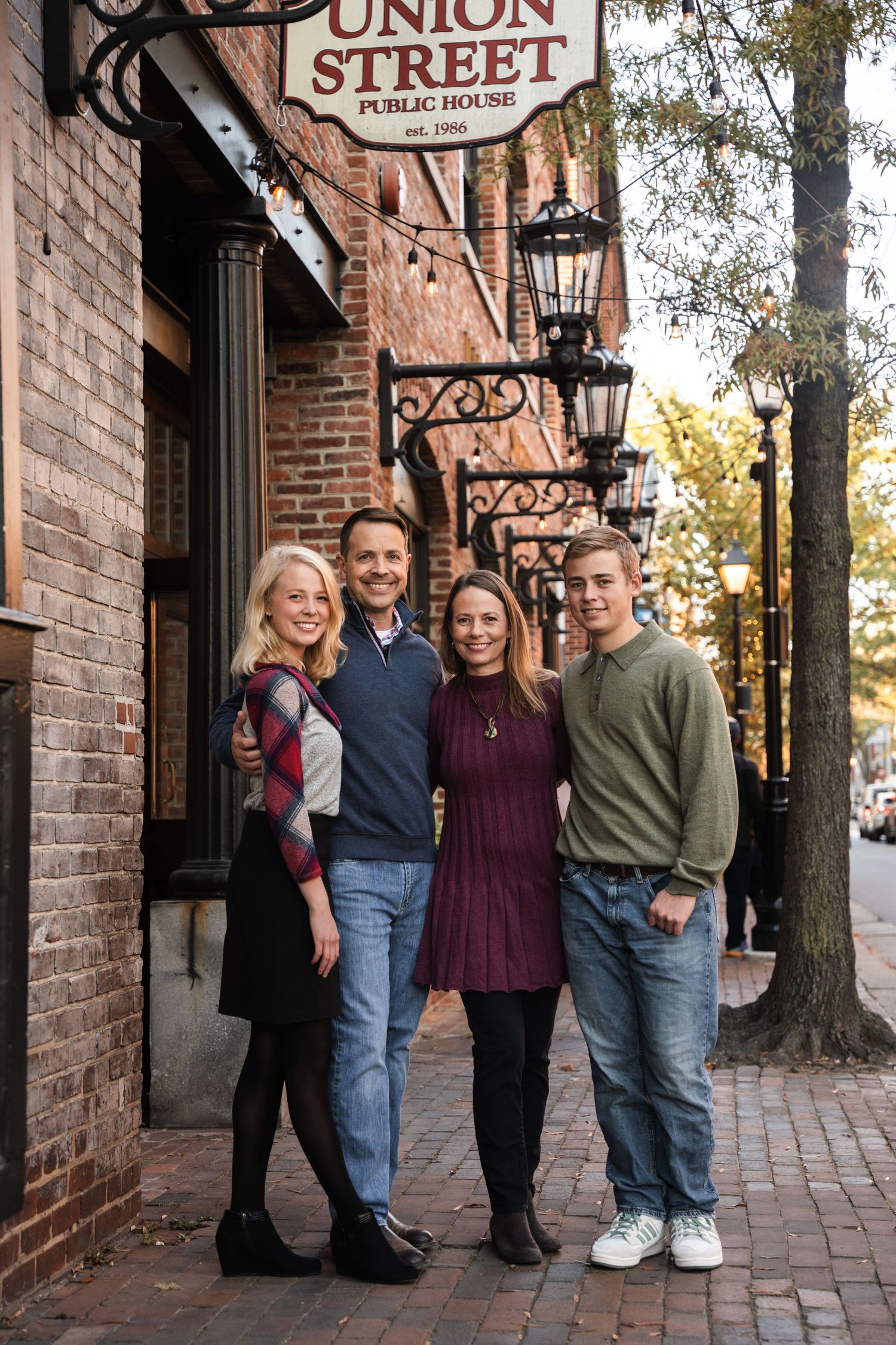 A group stands together on a brick sidewalk outside Union Street Public House in casual attire.