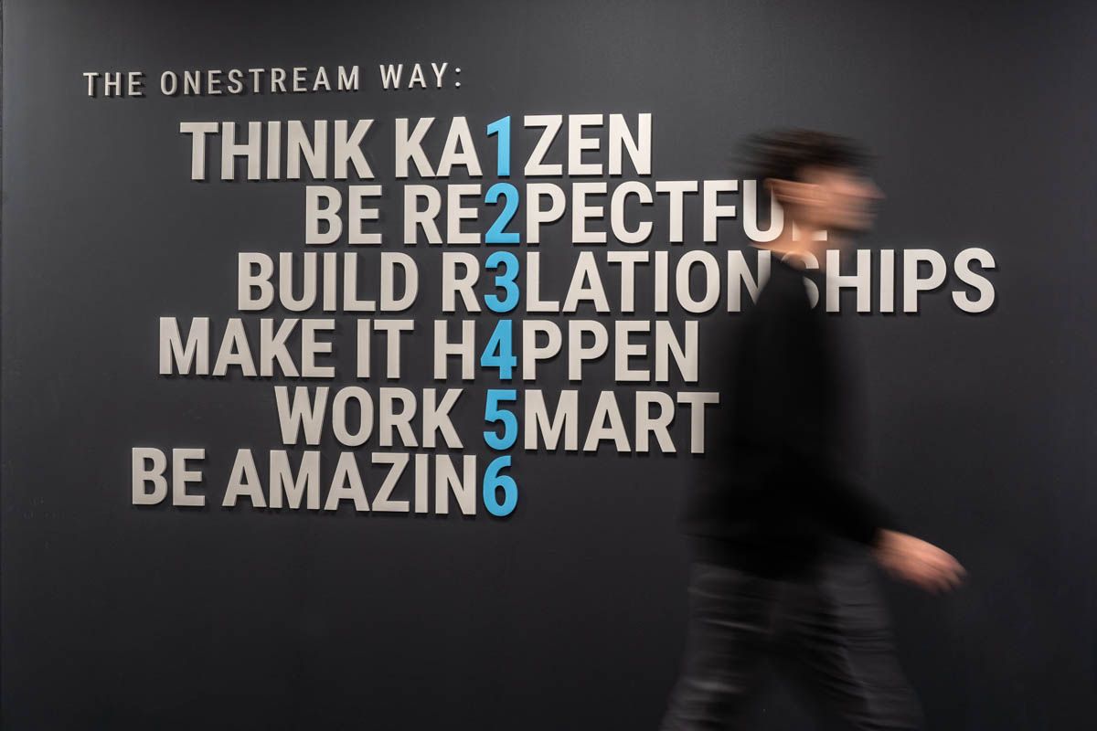 Motion blur of person walking past motivational text wall displaying company values and principles.