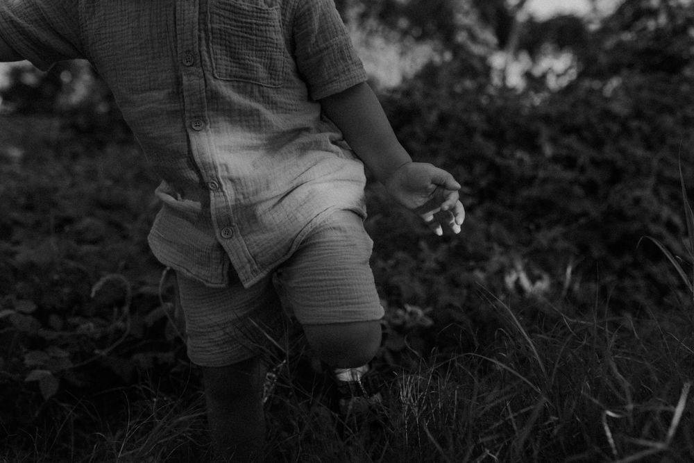 Black and white photo of boy walking through grass in Mount Isa