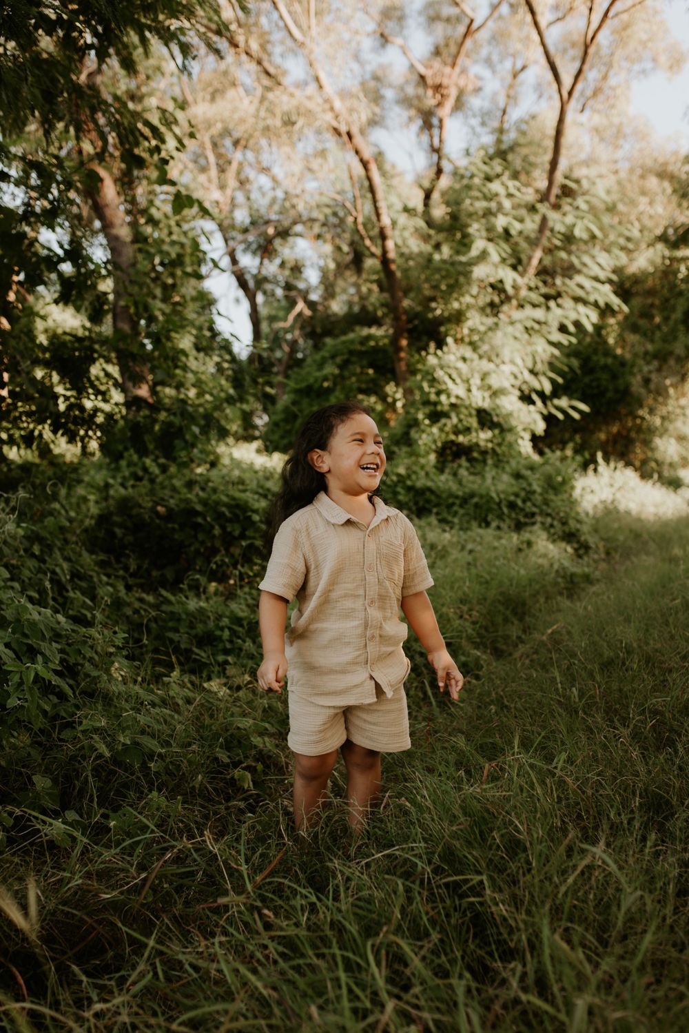 Young boy standing amongst the green bushes in Mount Isa