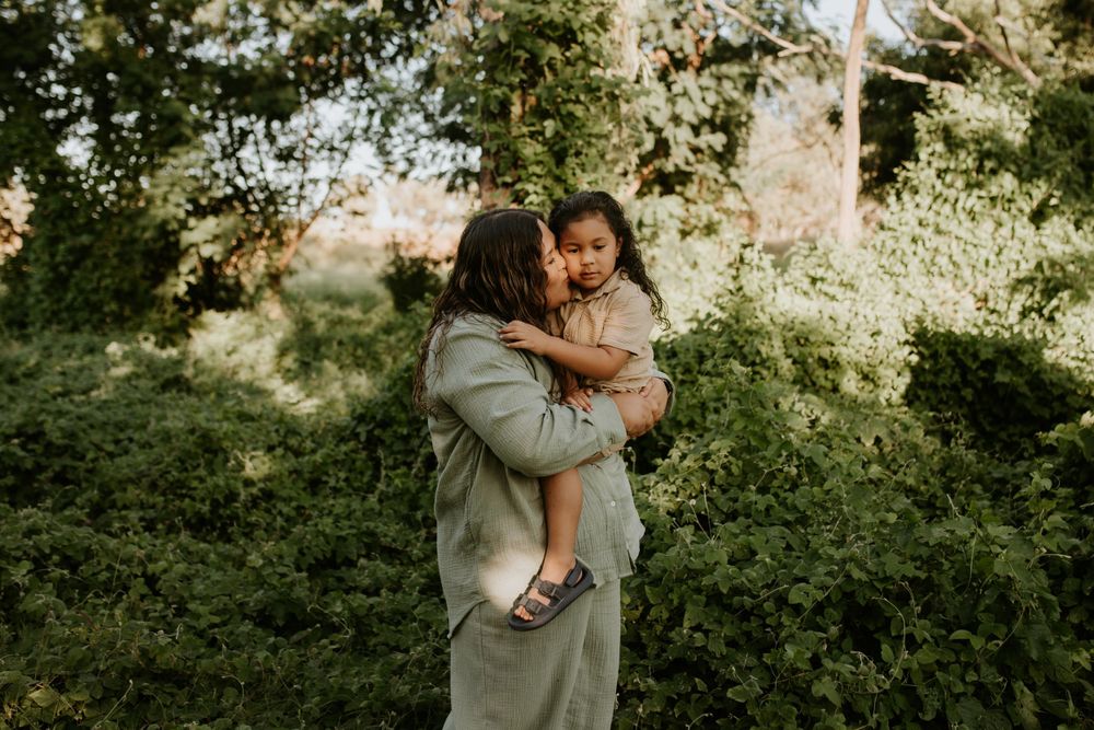 Mother kisses son on cheek amongst the greenery of Mount Isa