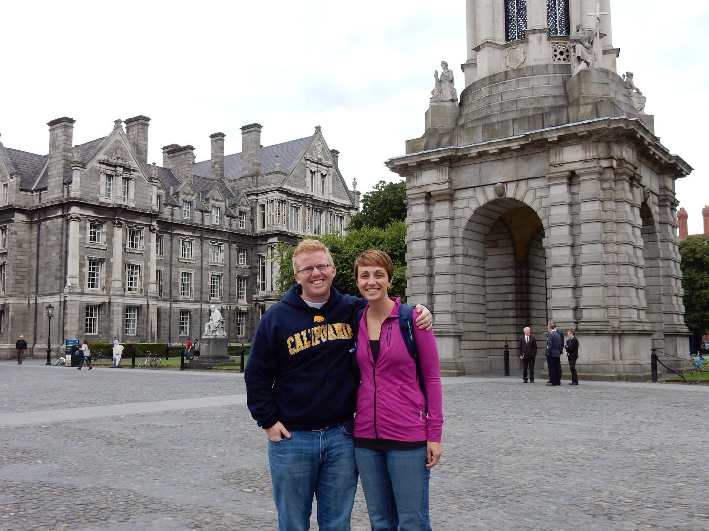 couple smiles in front of Trinity College in Dublin, Ireland