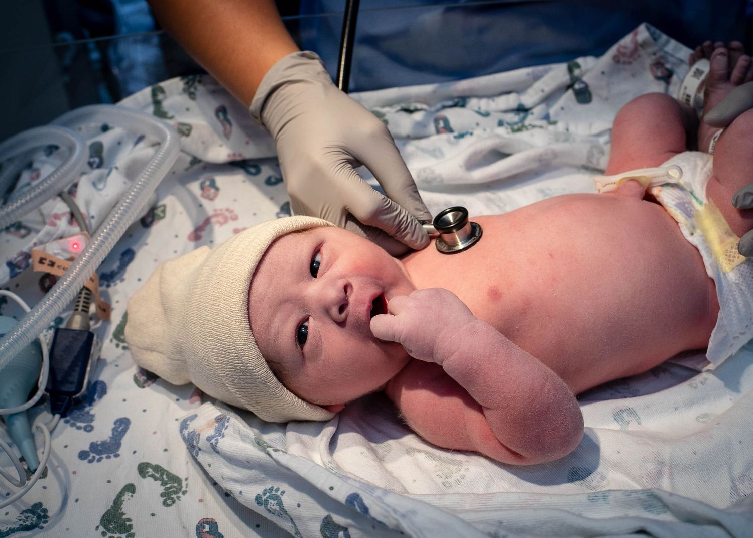 Newborn boy on a warmer at the hospital while the nurse listened to his heart with a stethoscope at UnityPoint.