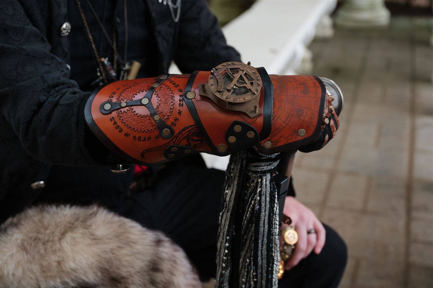 Detailed view of a steampunk-style leather arm bracer with brass embellishments and decorative patterns.