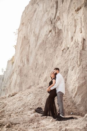 Romantic photoshoot against a dramatic limestone cliff backdrop at sunset.