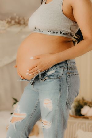 Casual maternity photos featuring distressed denim jeans and Calvin Klein top.
