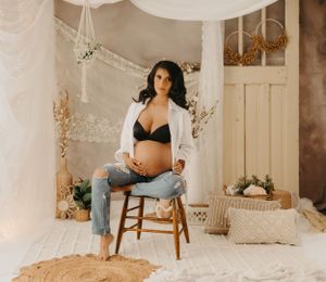 Indoor maternity photoshoot with soft lighting and vintage-inspired decor.