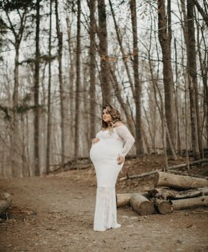 Person in white dress twirling in wooded forest setting.