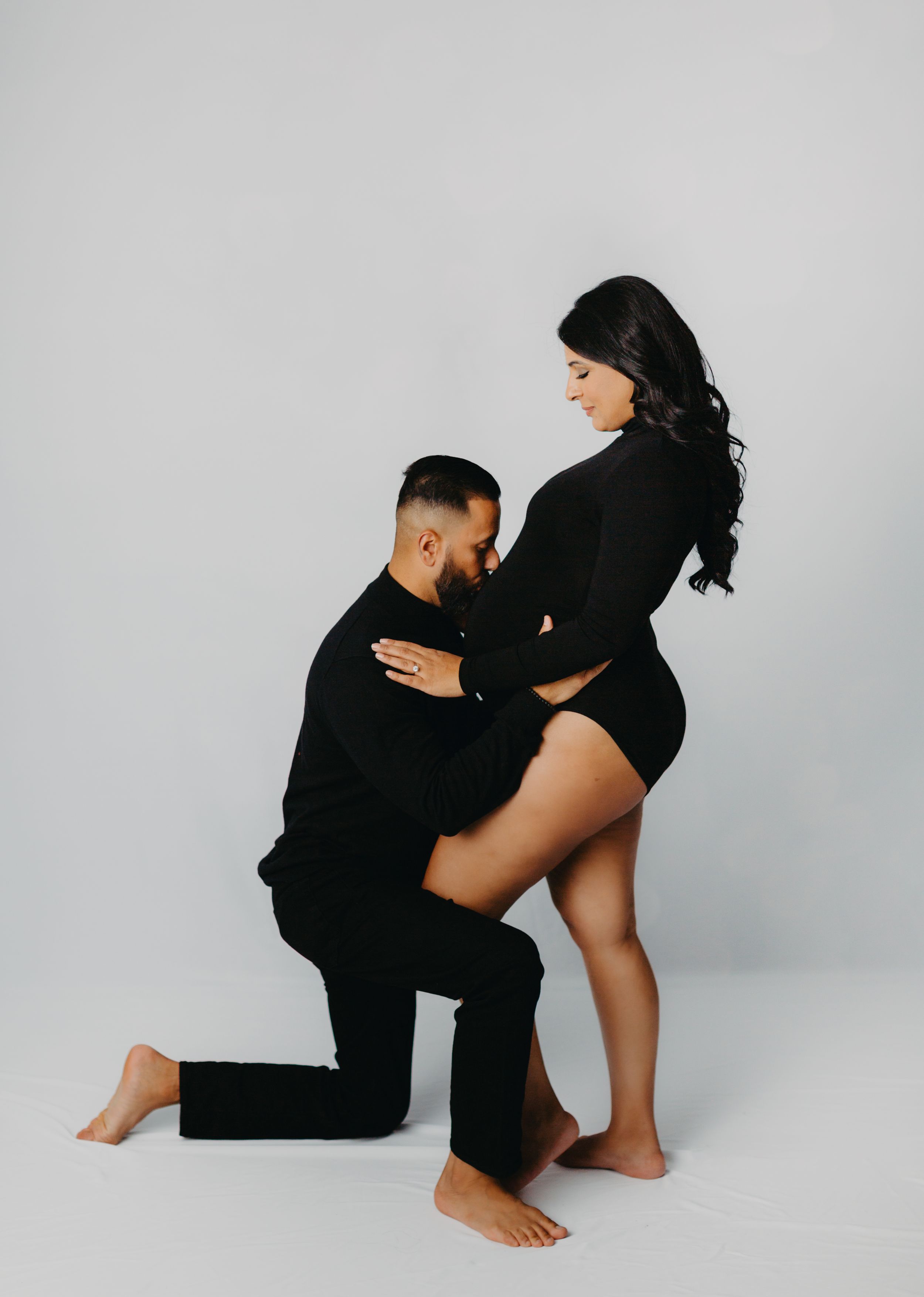 Artistic black and white maternity photos showing intimate poses against a light background.