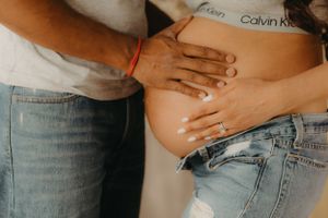 Close-up maternity photos showing hands on baby bump wearing Calvin Klein.