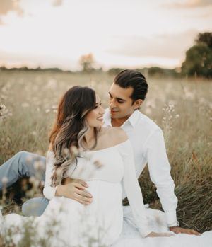 Romantic couple poses among wildflowers during golden hour photo session.