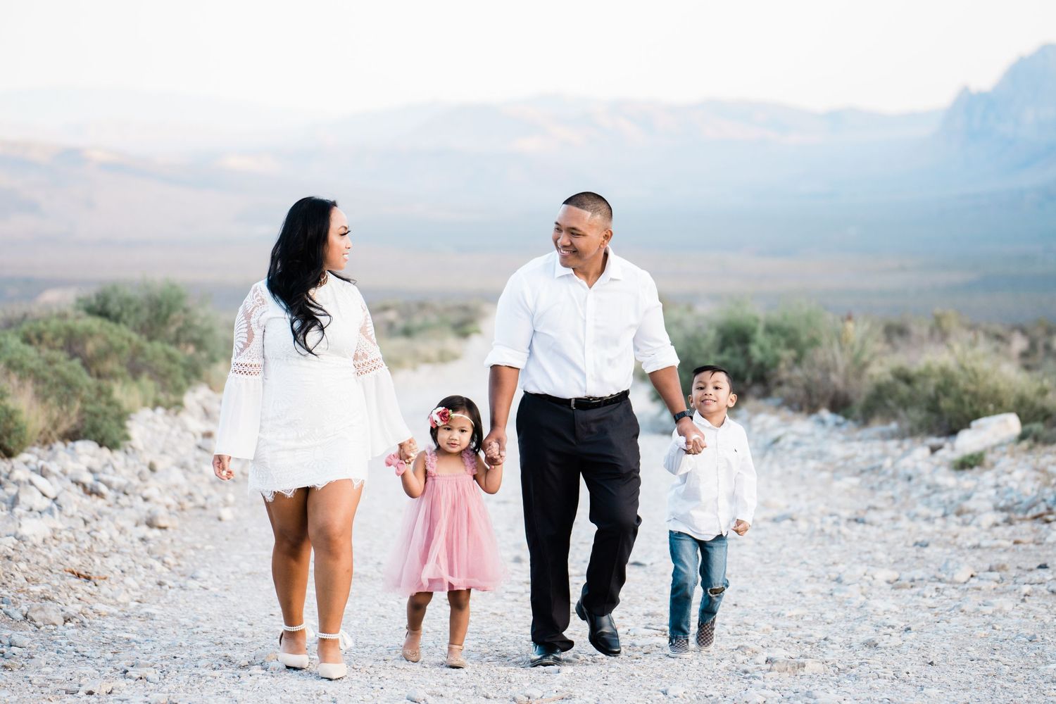 Family walking together on a desert path with mountains in the background.