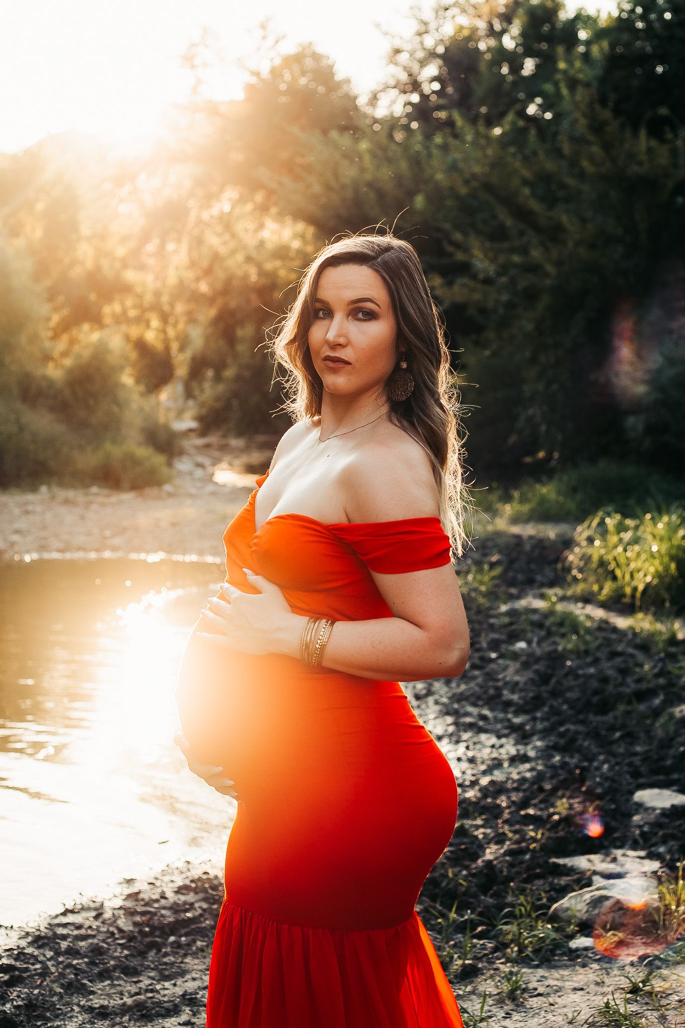 Pregnant woman in a red dress at golden hour