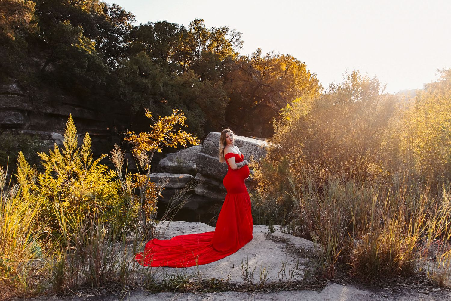 Glorious maternity portrait of a woman in red dress at golden hour