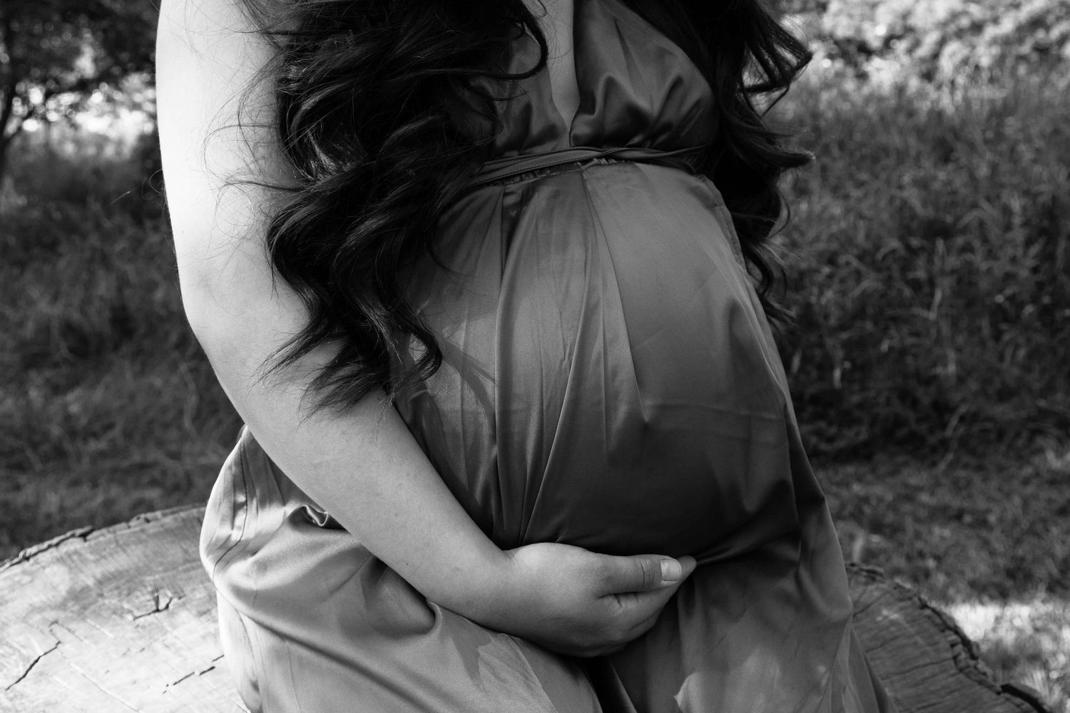 Black and white shot of expecting mother holding her pregnant belly