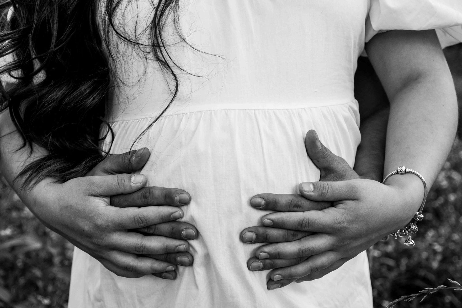 Father-to-be holding expecting mother's pregnant belly from behind