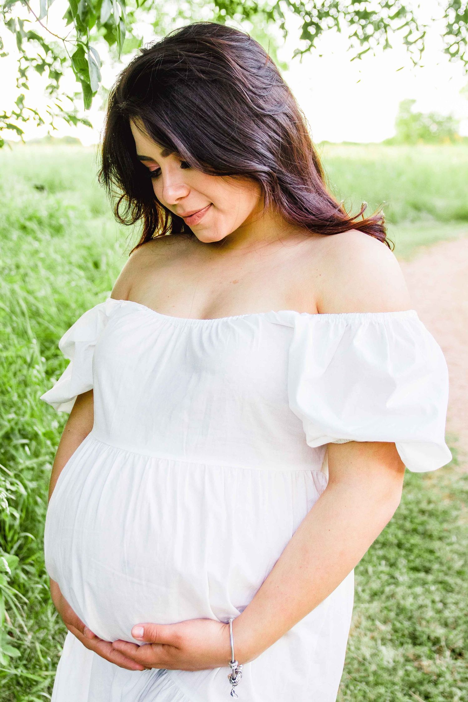 Pregnant woman in a white dress holding her pregnant belly