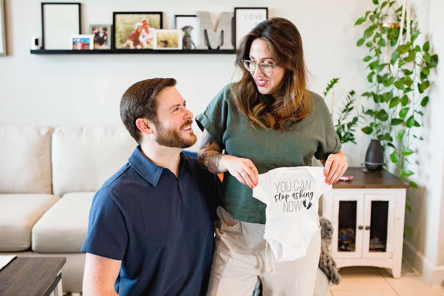 Expecting mother holds up baby onsie to announce pregnancy