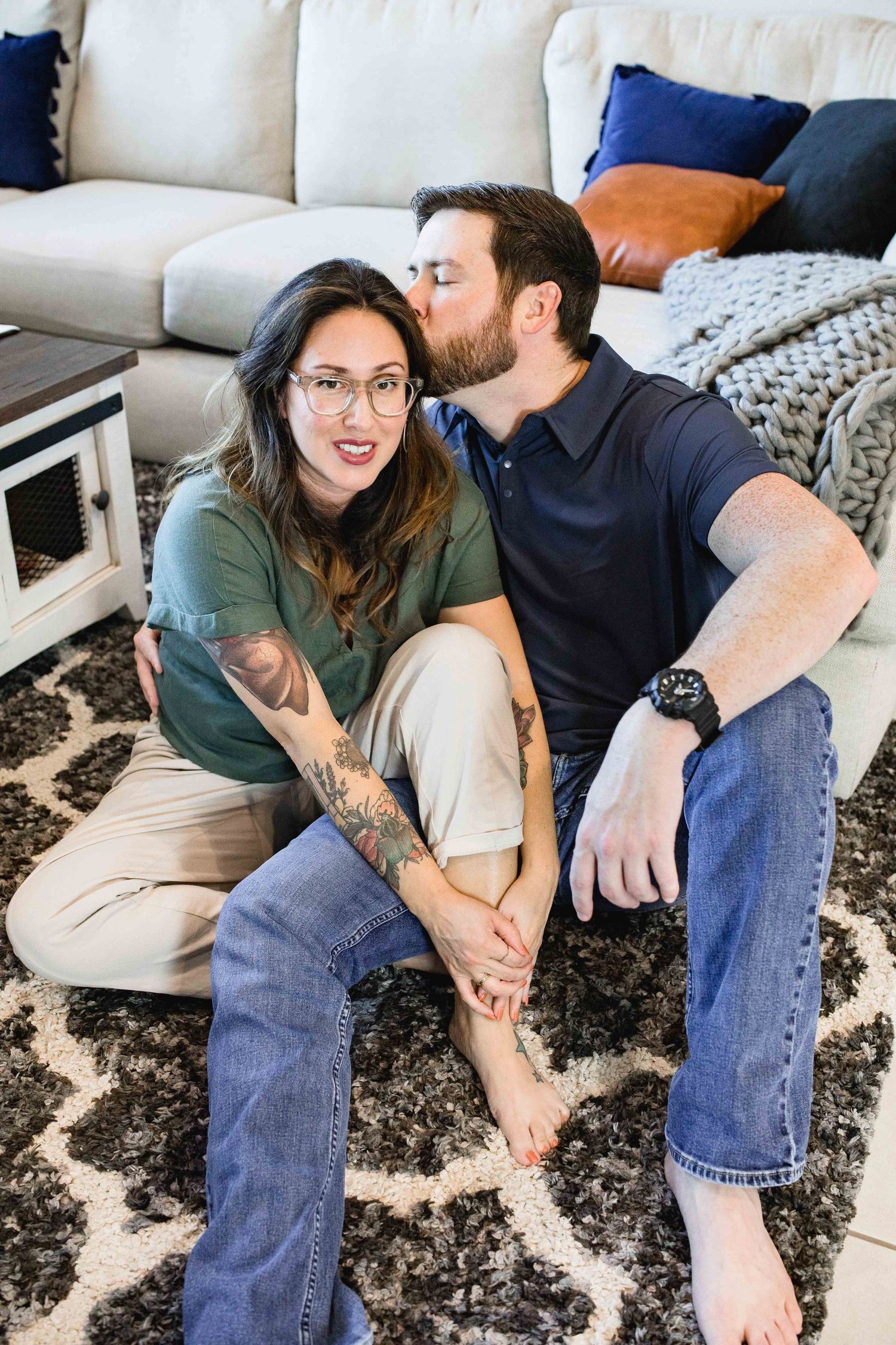 Man kissing wife on her temple while sitting on the floor