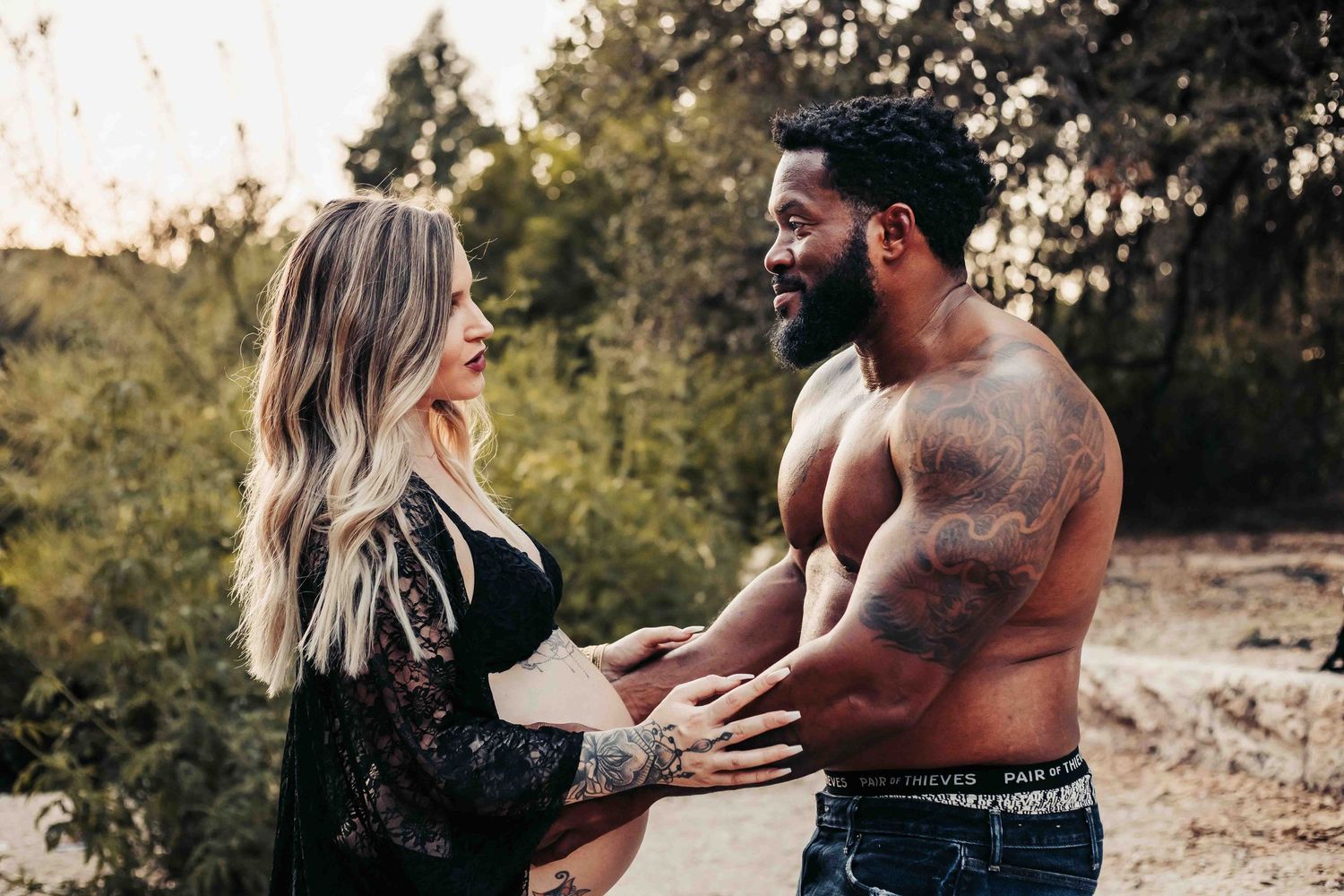 Father to be holding expecting mother's belly at a park