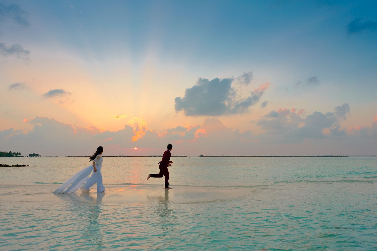Bride and Groom running at the beach during sunset