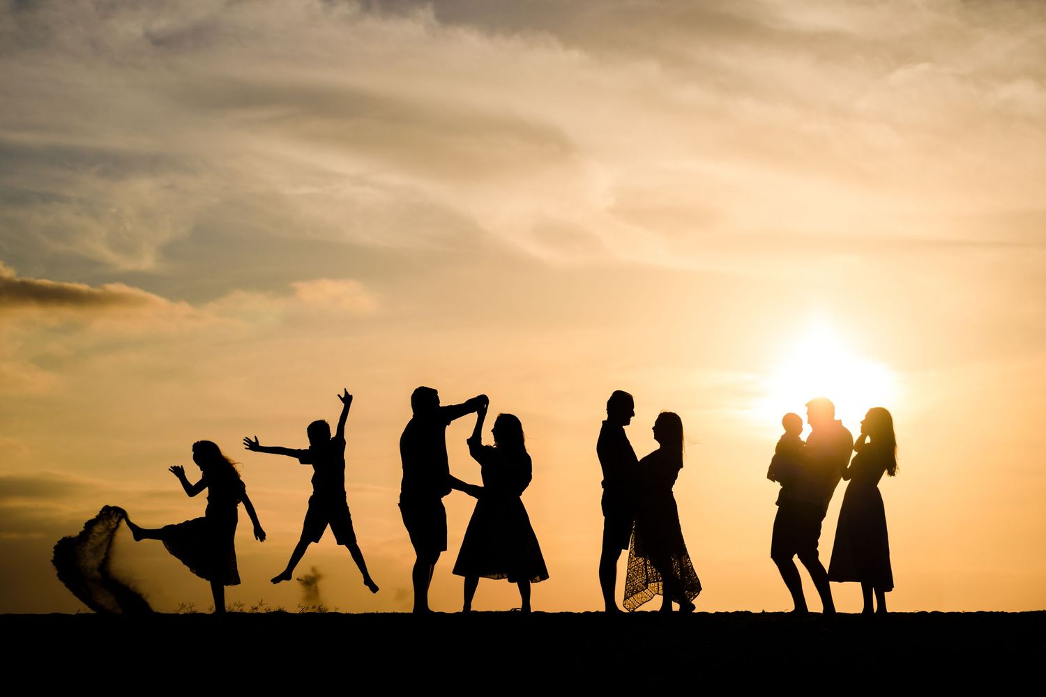 Silhouettes of dancing couples against a golden sunset sky creating joyful poses.