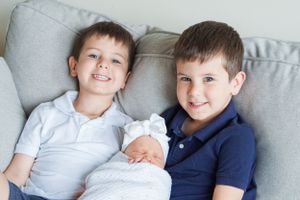 Young boys in casual shirts posing together on grey sofa.
