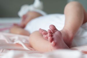 Close up of tiny baby feet and legs on pink bedding.