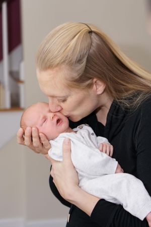 Tender moment between parent and newborn baby in white clothing.