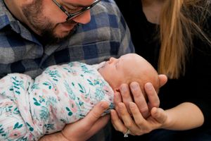 Gentle moment with newborn wrapped in teal floral swaddle blanket.