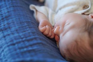 Close-up of a sleeping infant against blue textured fabric.
